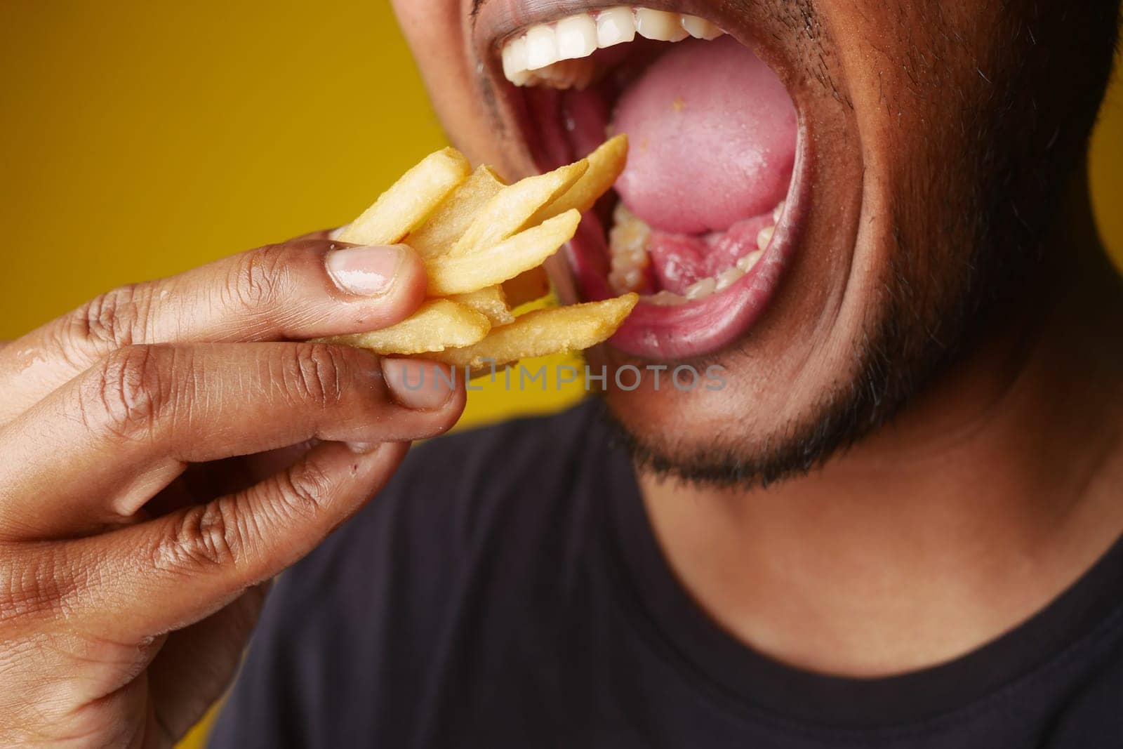 hungry man eating fries closeup by towfiq007