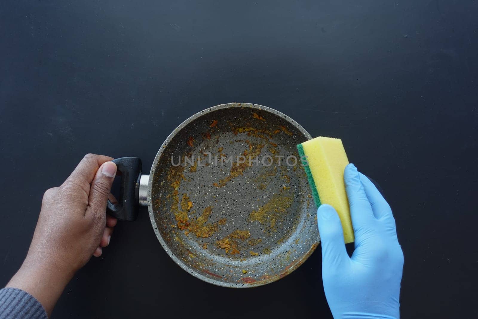 Hand with sponge cleaning dirty pan ,