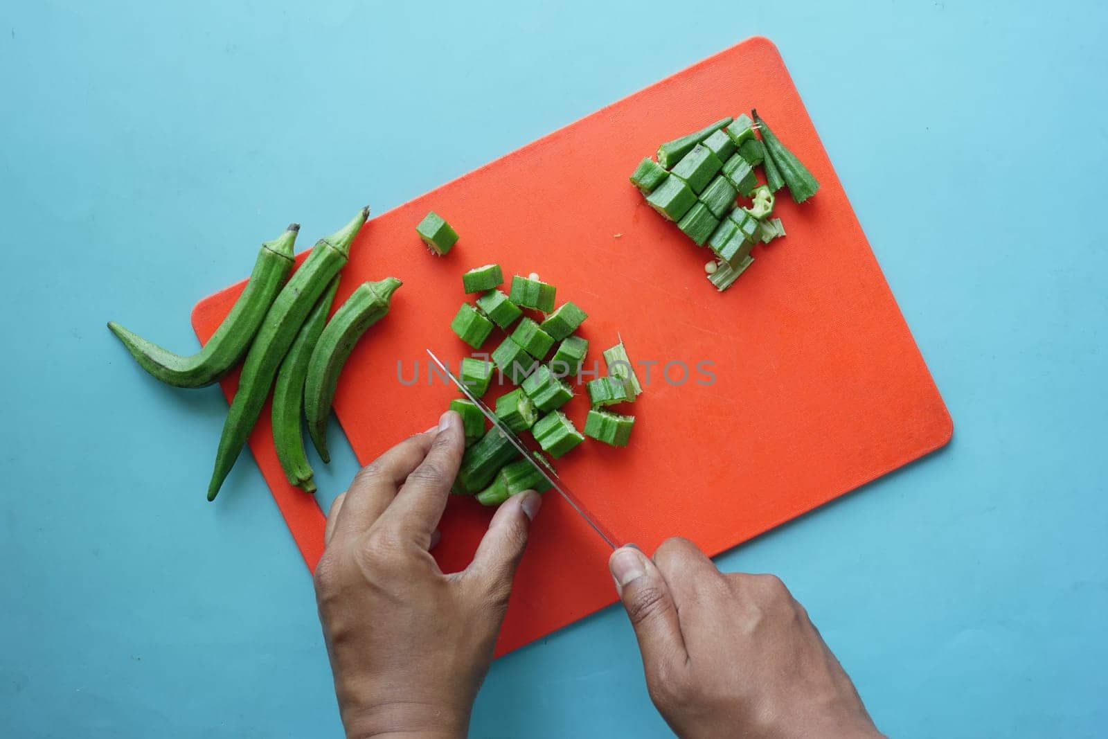 top view of ladies fingers or bhindi cutting on chopping board ,