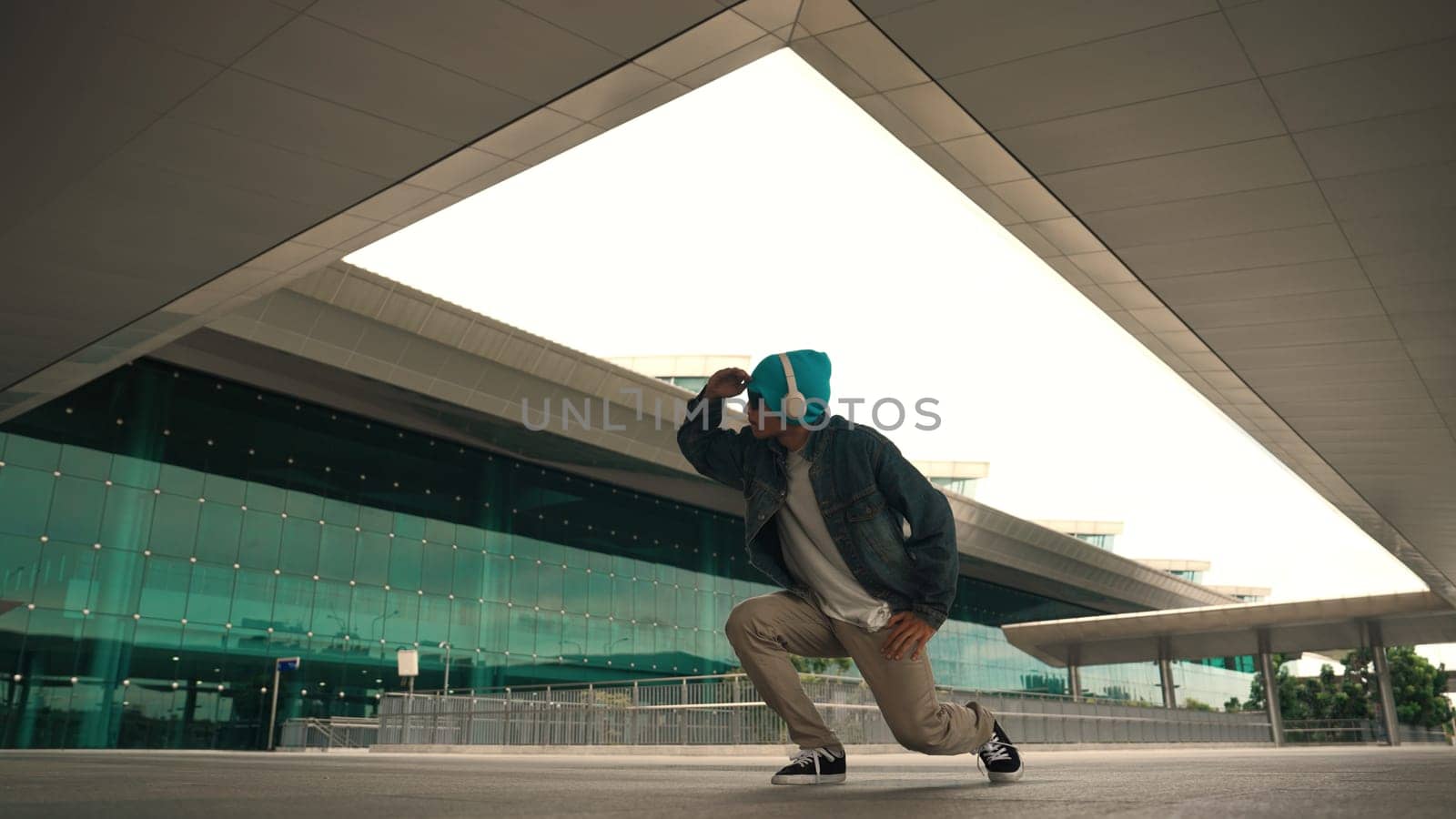 Motion shot of happy hipster practice b boy dance with stylish cloth at building. Dancer enjoy show footstep performance. Modern lifestyle, break dancing. Slow motion. Outdoor sport 2024. Sprightly.