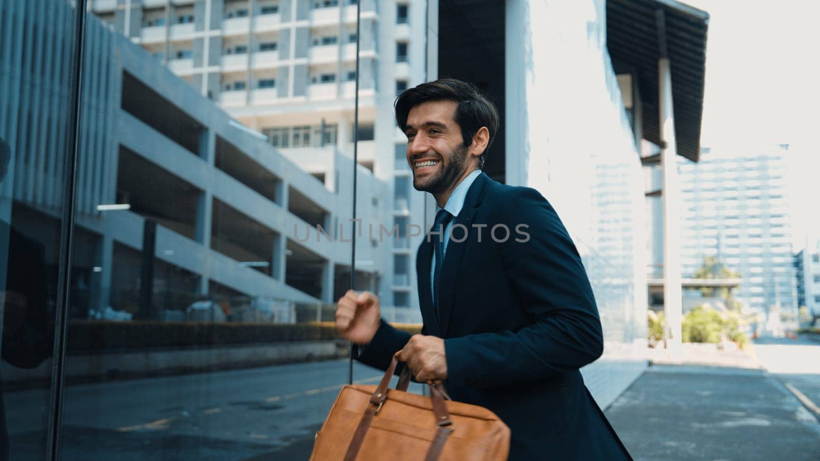 Skilled smart business man dancing with joyful while walking in glass wall. Project manger receive a good news, getting promotion, getting a successful job while express feeling of overjoy. Exultant.