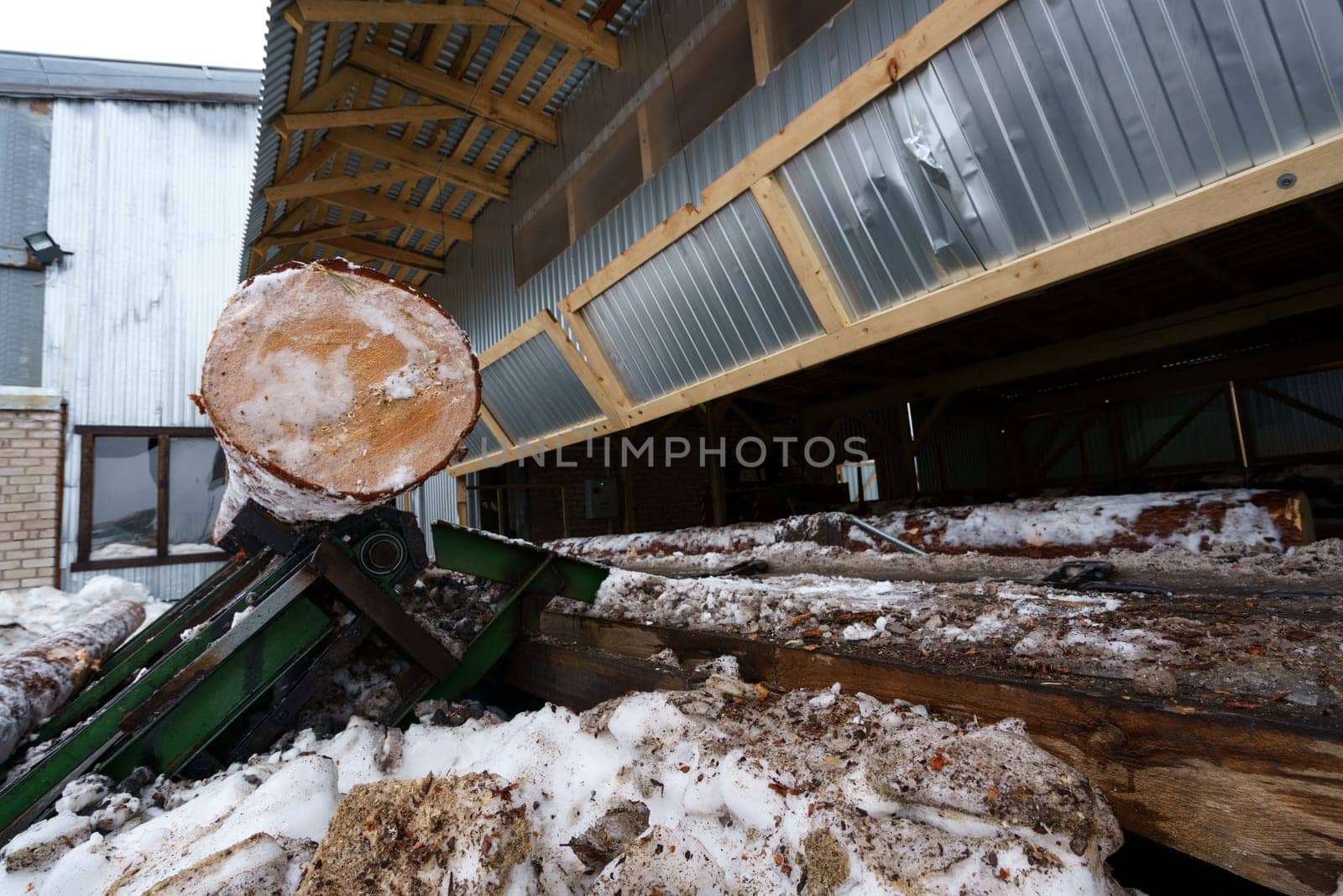 Sawmill in winter time. Image of log under roof