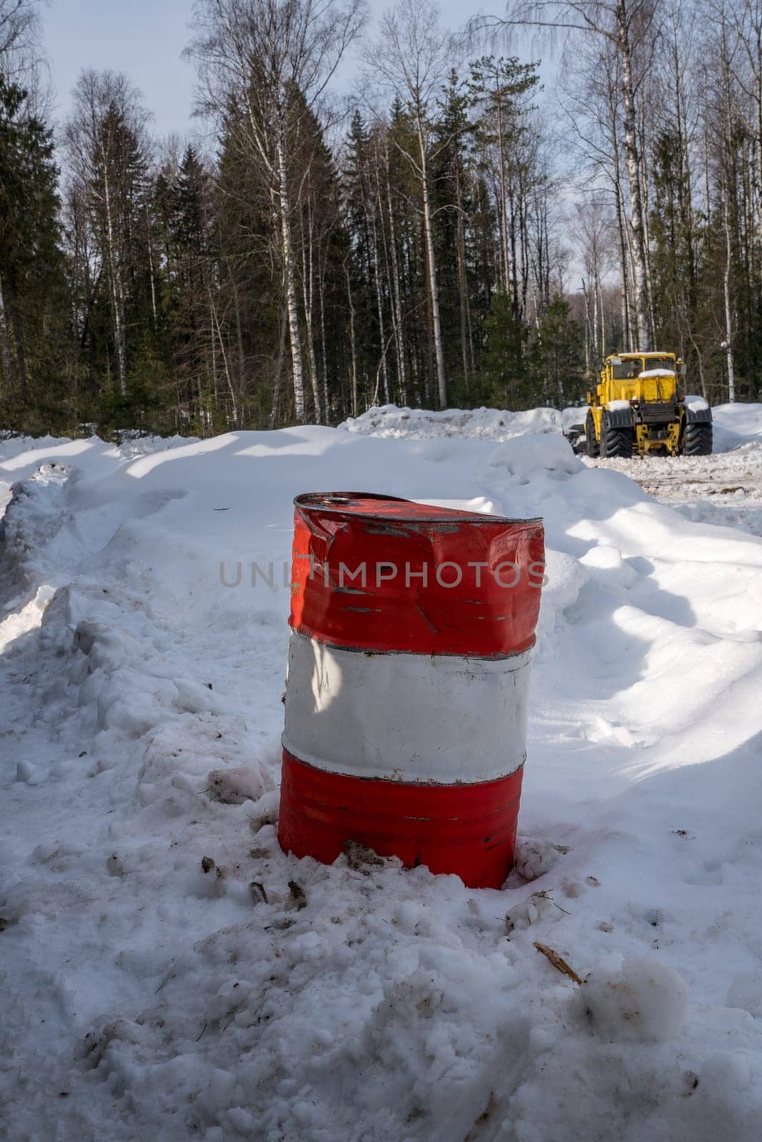 Image of striped barrel and working snowplow on background