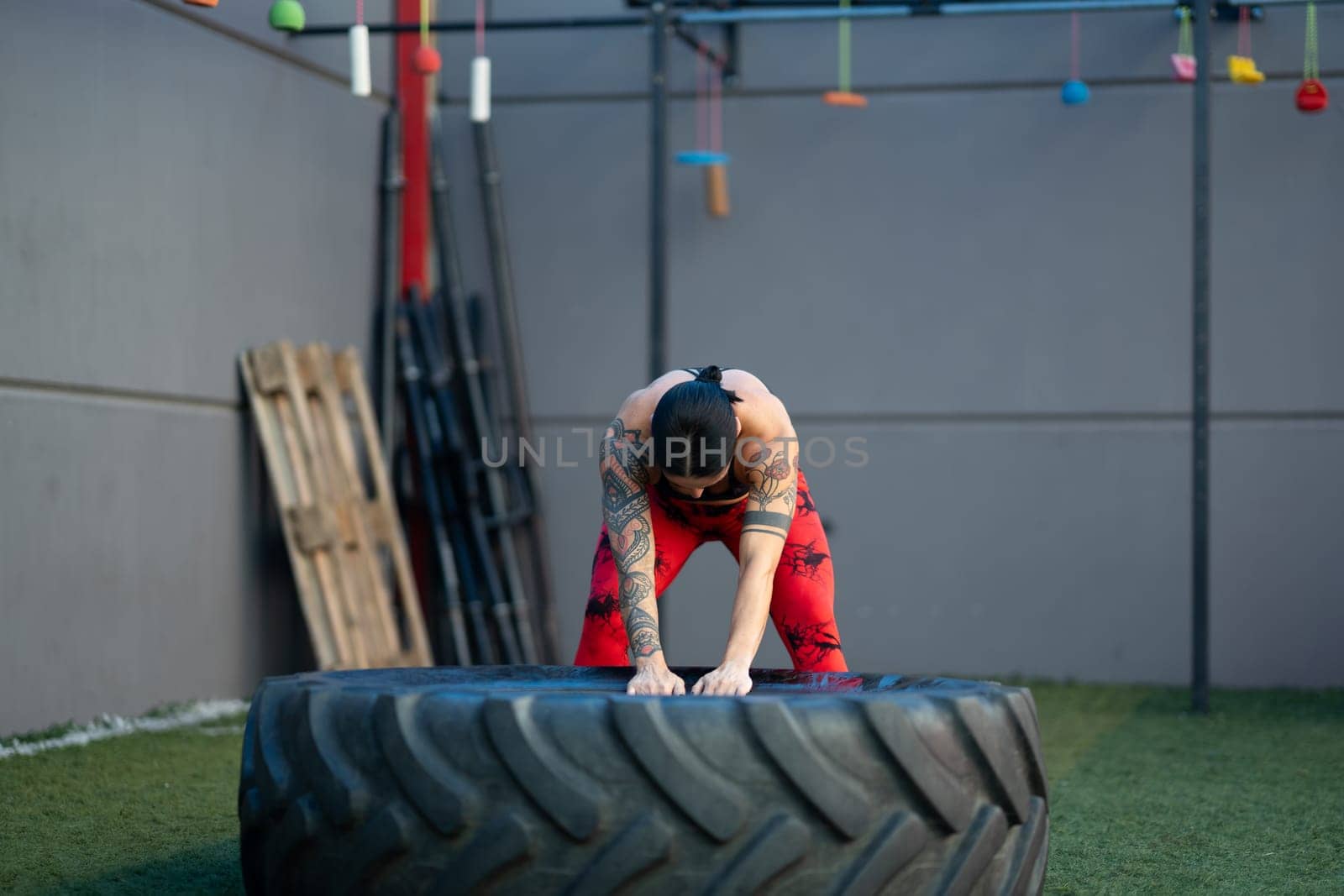 Horizontal photo with copy space of a strong mature woman training using huge wheel in a gym