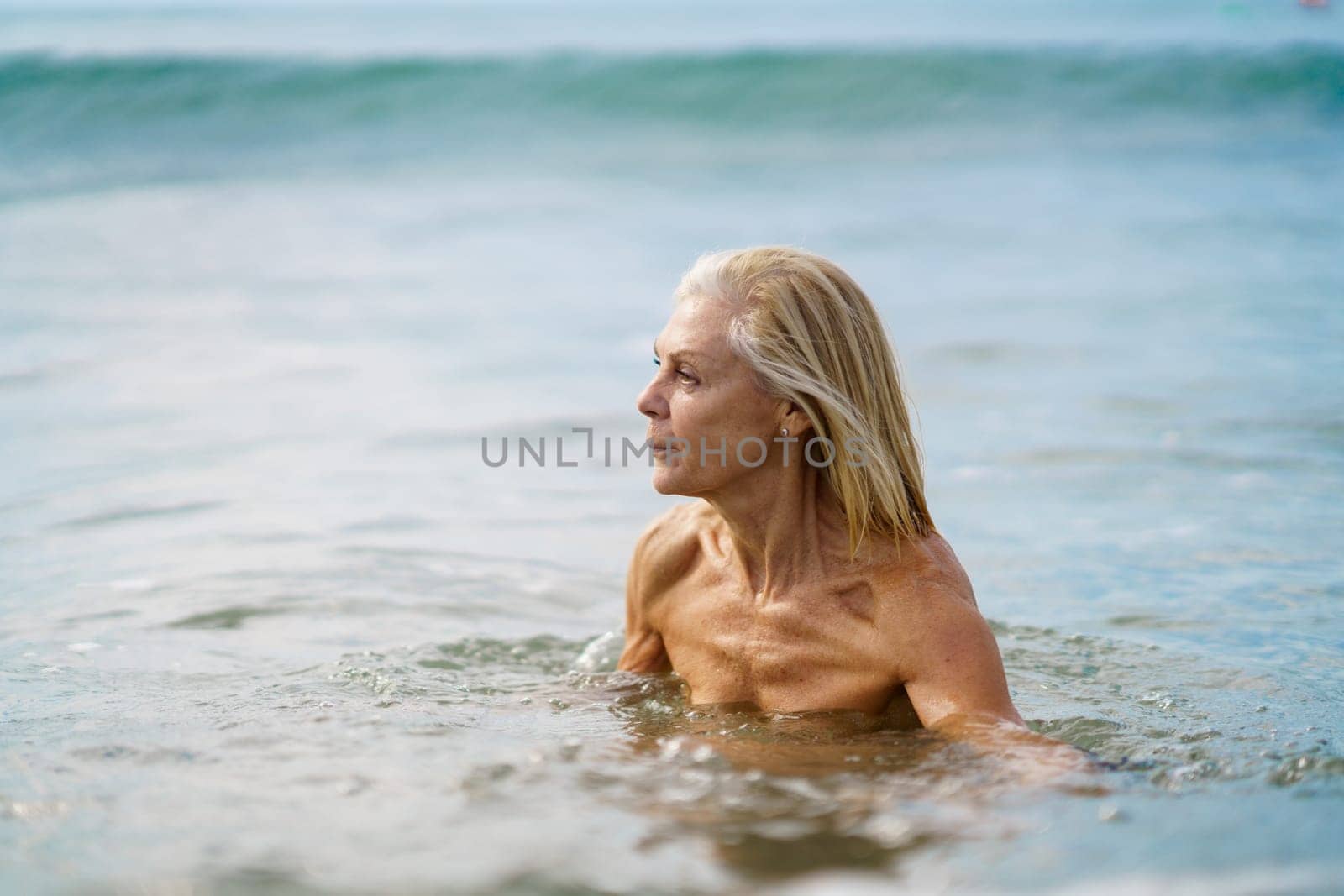 Mature woman in good shape bathing in the sea. Elderly female enjoying her retirement at a seaside retreat.