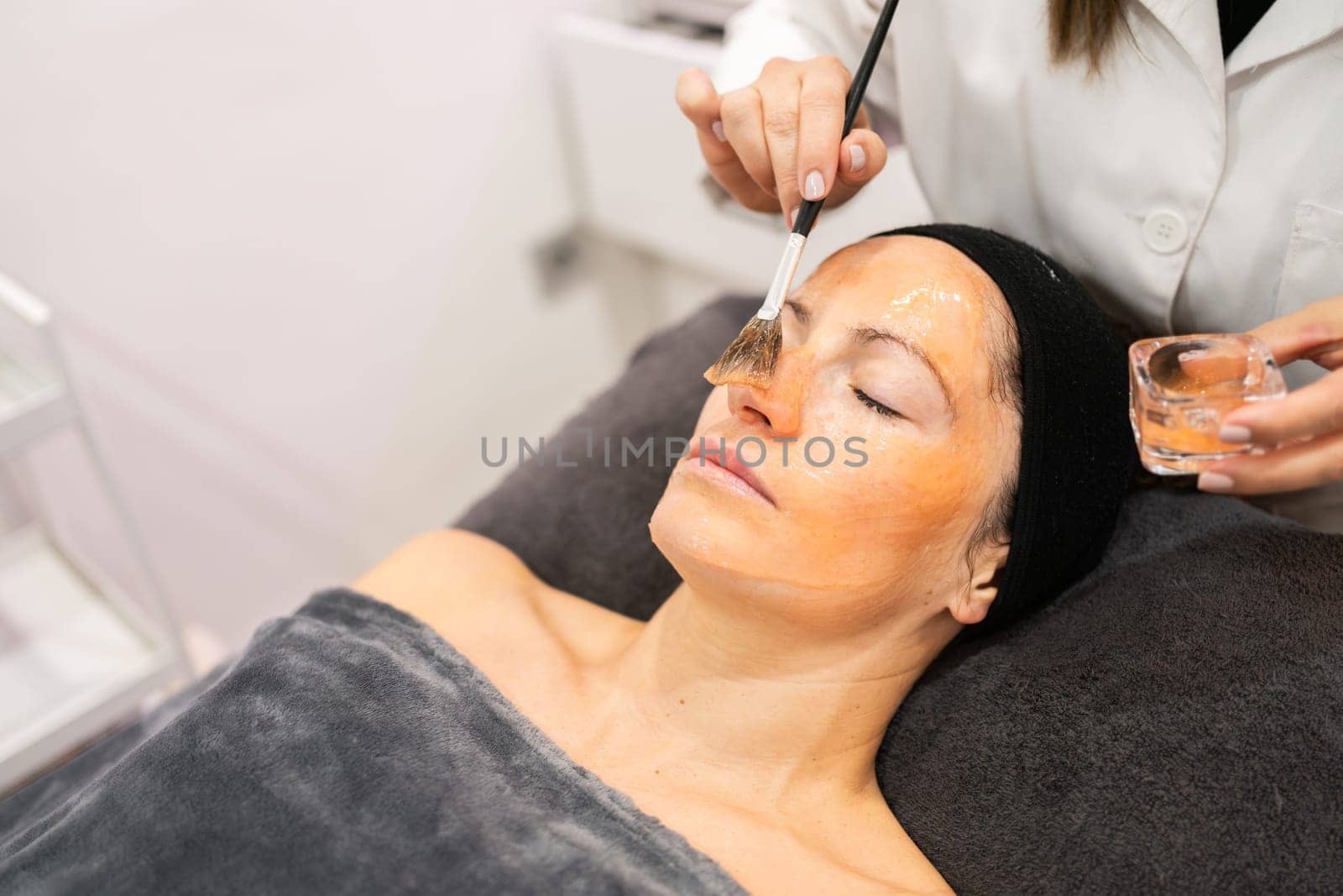 Lady with closed eyes getting facial treatment in beauty salon by javiindy