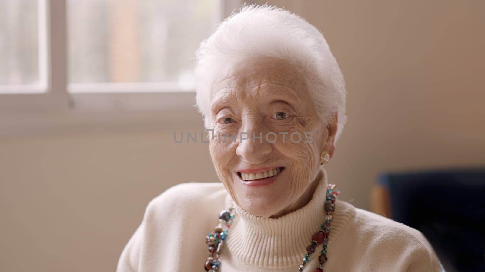 Old woman with white hair smiling at camera in a geriatric