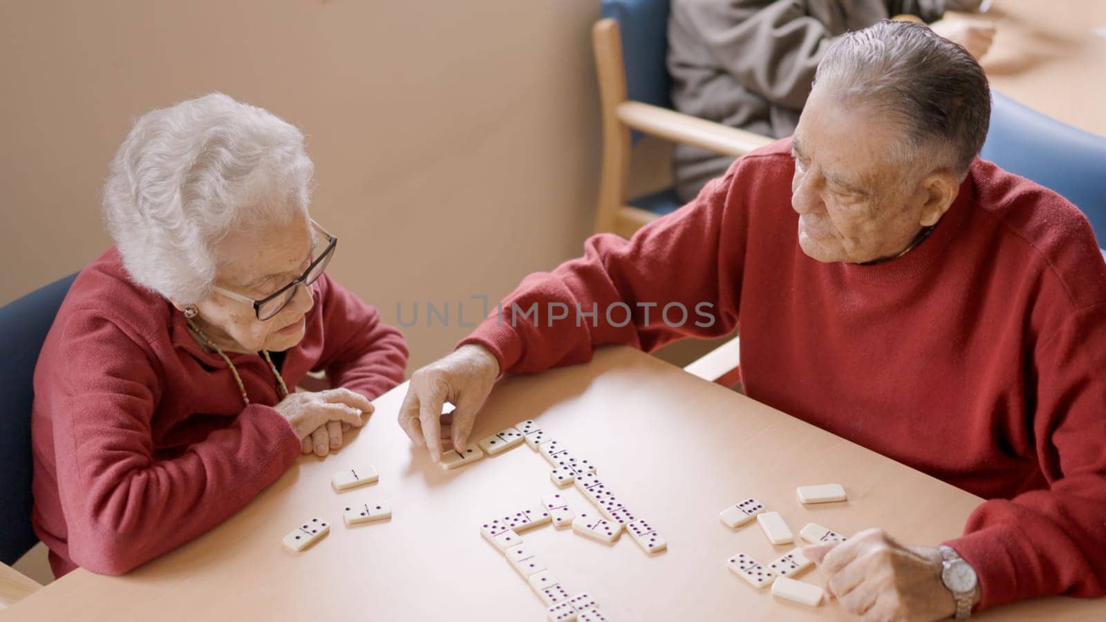 Senior man playing dominoes with old friend in geriatric by ivanmoreno