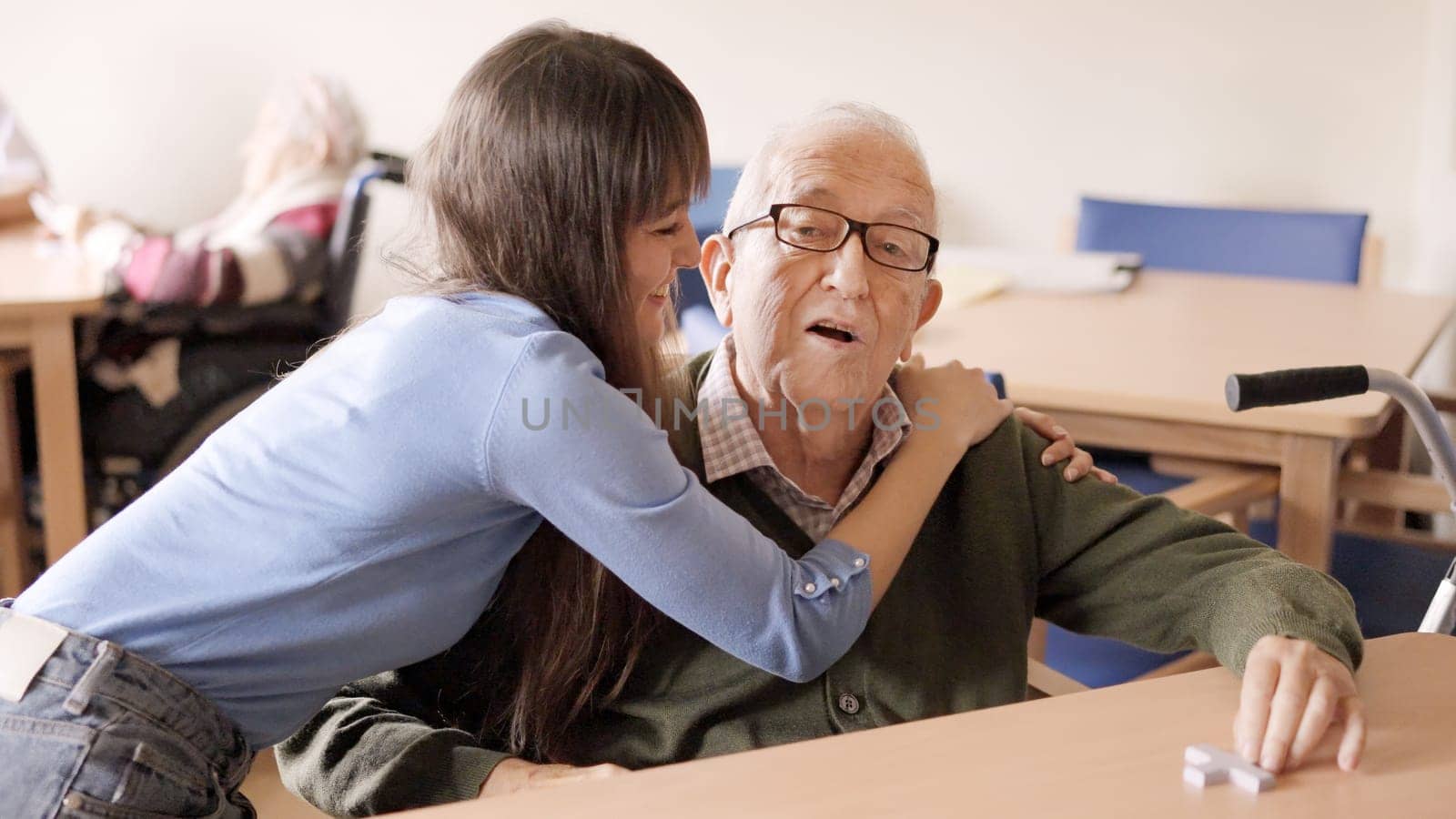 Granddaughter looking at her grandfather with a happy smile while hugging him