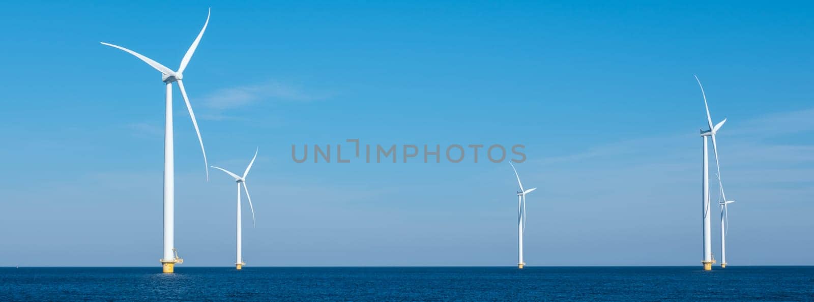 A mesmerizing view of a row of wind turbines gracefully spinning in the vast ocean, capturing the power of renewable energy. Windmill turbines at sea, green energy transition in Europe