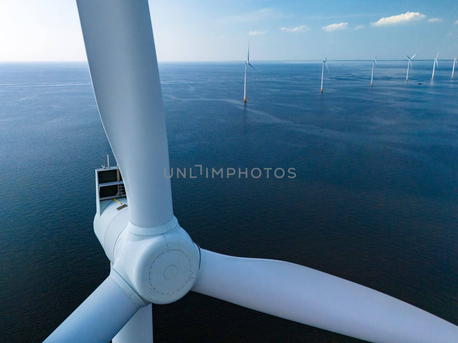 A lone wind turbine gracefully spins in the vast expanse of the ocean, harnessing the power of the wind in the Netherlands Flevoland by fokkebok