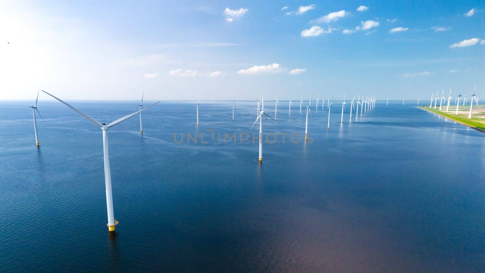 A serene large body of water is dotted with numerous windmills spinning gracefully in the wind, creating a mesmerizing and sustainable energy dance.