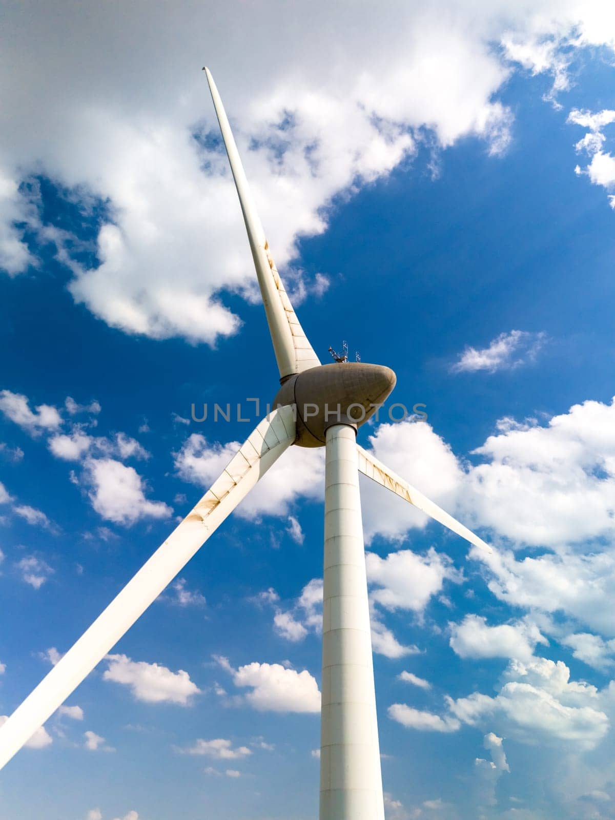 A majestic wind turbine is set against a vibrant blue sky, rotating gracefully as it harnesses the power of the wind in the Netherlands Flevoland.
