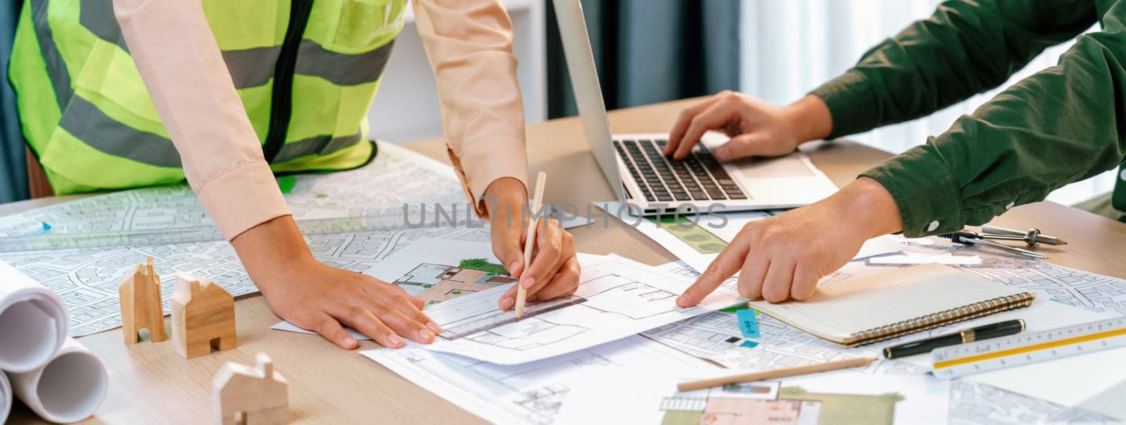 Professional engineer team discussion about house design on meeting table with architectural equipment and blueprint scatter around at modern office. Focus on hand. Closeup. Delineation.