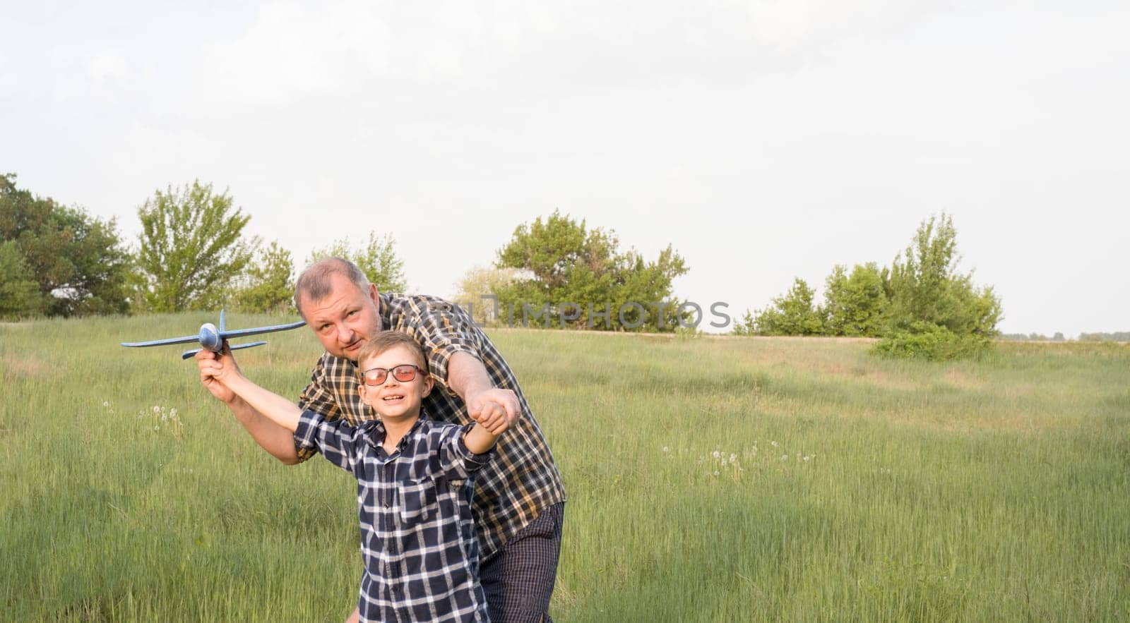 Father and son having fun in the field playing with an airplane by Ekaterina34