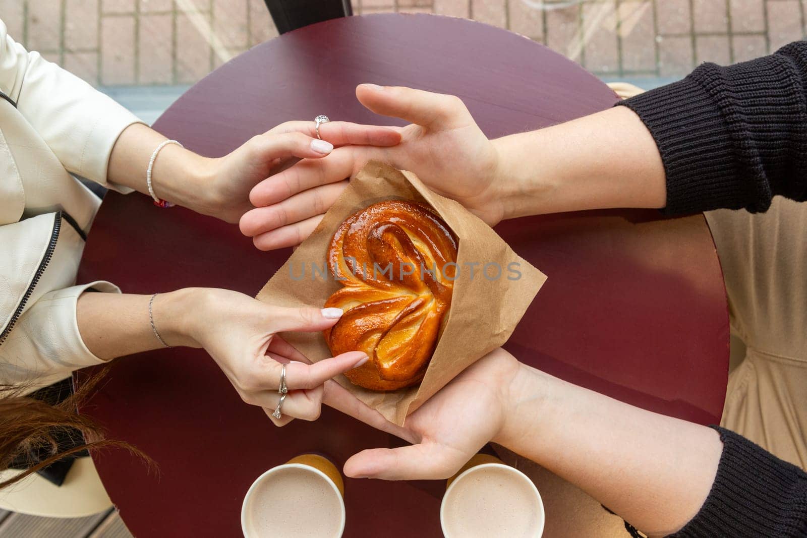 A guy with a girl on a date in a cafe. The guy hands the girl a heart-shaped bun.