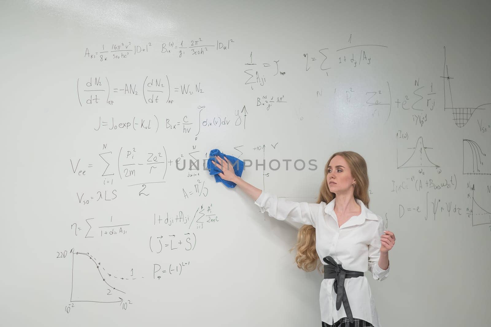 Caucasian woman erasing formulas from white board