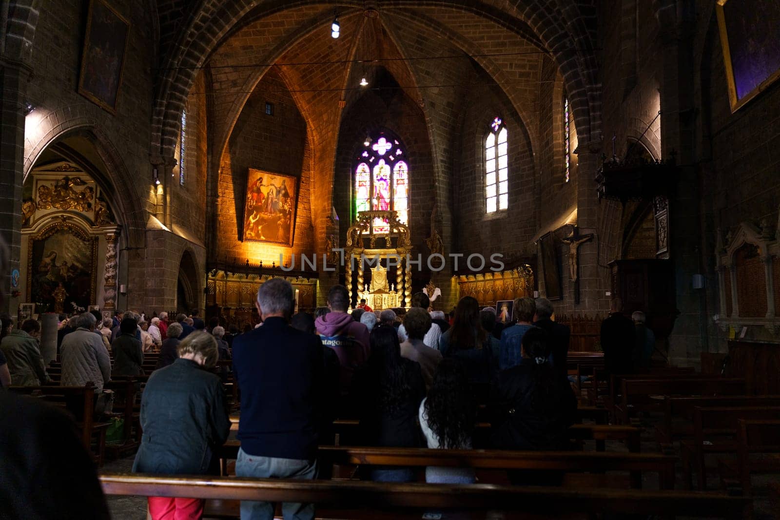 Langeac, France - May 27, 2023: A diverse group of people are standing in front of a grand Catholic church in France.