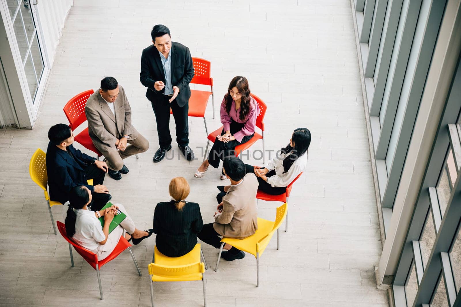 Top view of multiethnic professionals in bustling office engaged in teamwork and discussions. Businessman and businesswoman sit at conference leaving copy space. dynamic business meeting in progress. by Sorapop