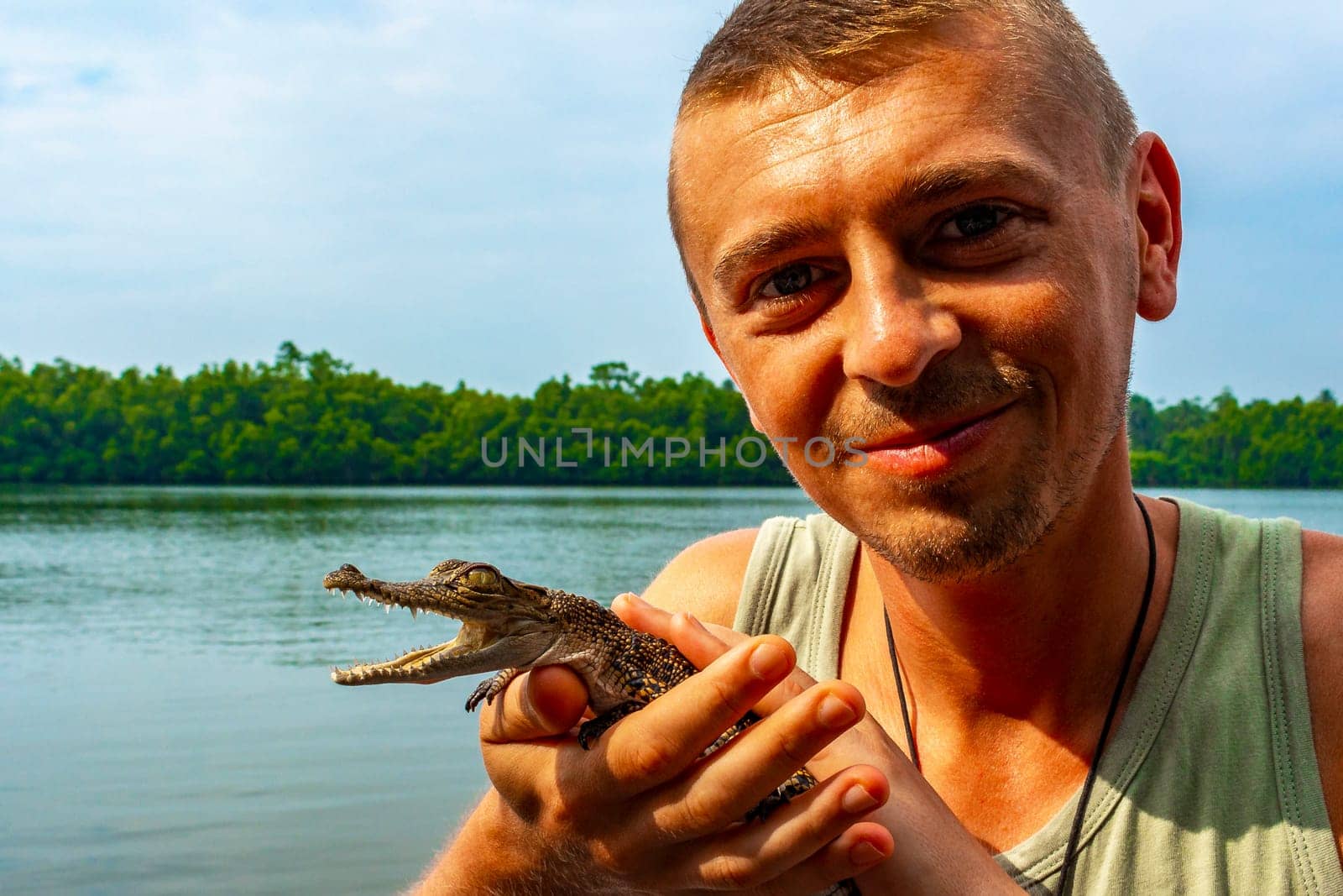 Man tourist with baby crocodile alligator Sri Lanka. by Arkadij