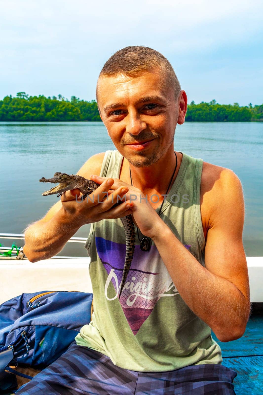 Man tourist with baby crocodile alligator Sri Lanka. by Arkadij