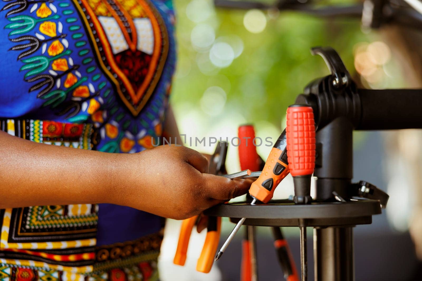 Close up of person choosing expert work tools for yearly outdoor bicycle maintenance. Detailed shot of female african american arm arranging an assortment of professional equipments.