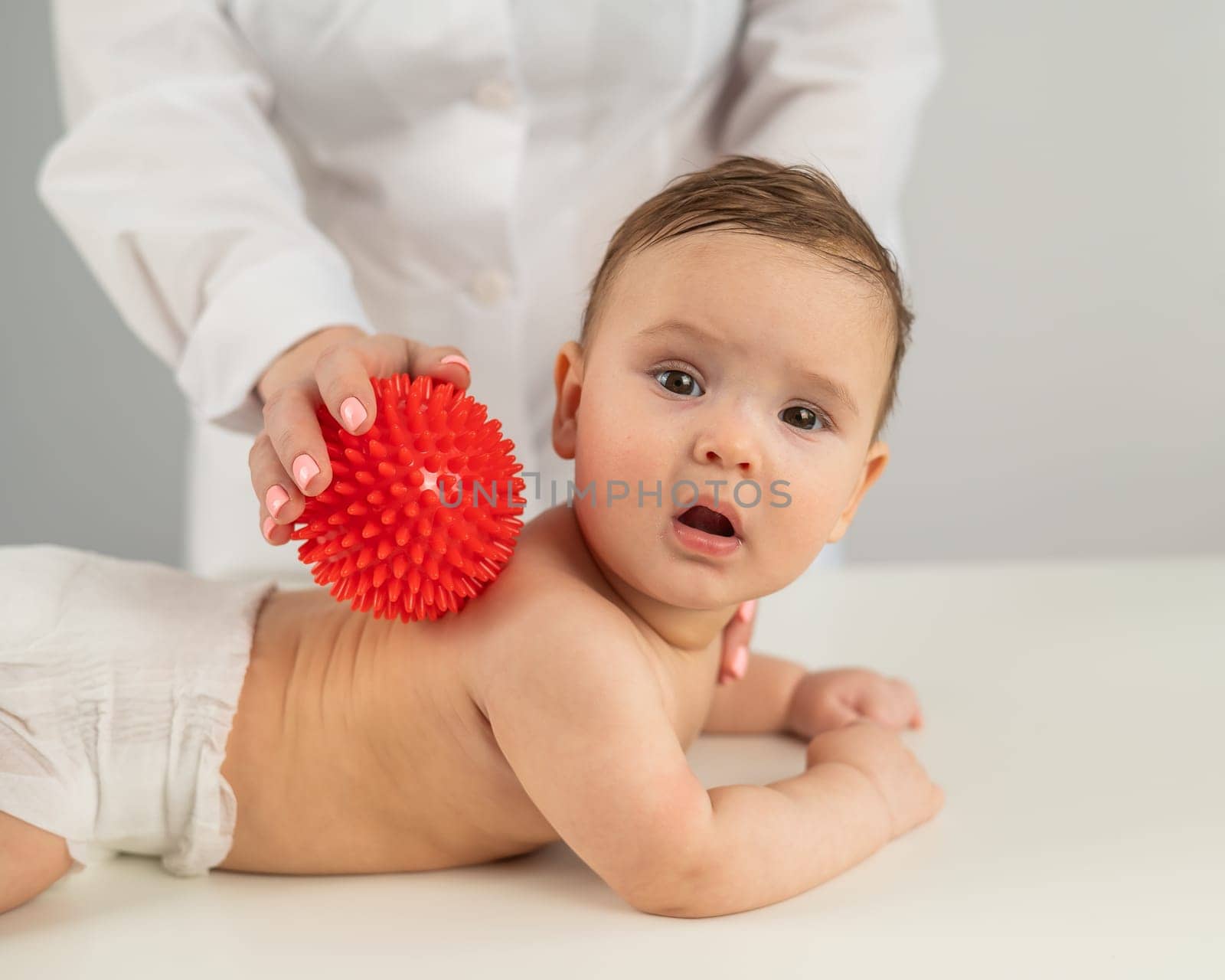 A doctor gives a child a back massage using a ball