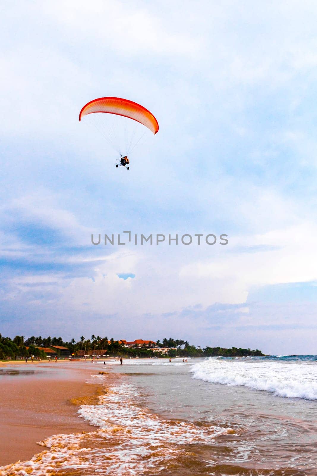 Beautiful beach with tropical nature sand water waves people fun parasols and sun loungers in Bentota Beach on Sri Lanka island.