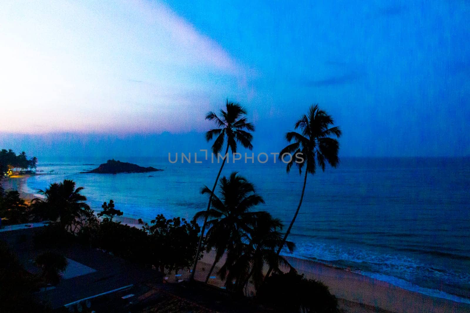 Beautiful golden colorful sunset sunrise at paradise tropical beach with palm trees waves and sea water view in Mirissa Beach Southern Province Sri Lanka.