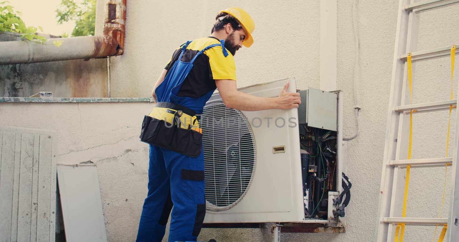 Expert wireman works on air conditioner by DCStudio