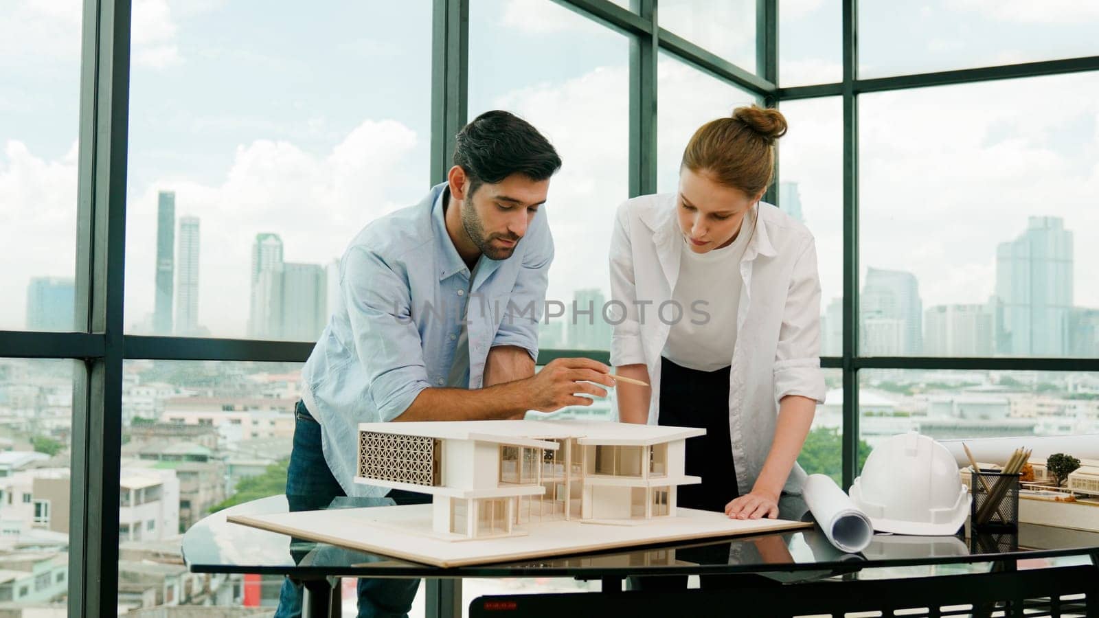 Cooperative architect engineer team working together to measure house model by using pencil. Successful caucasian interior designer team inspect architectural model construction. Design. Tracery