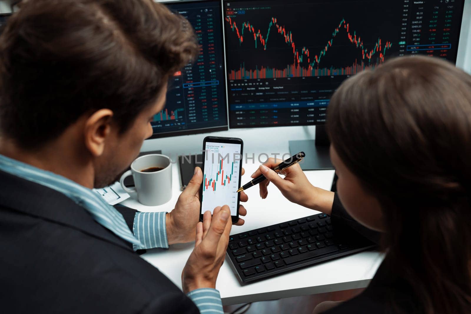 Focusing on phone with discussing dynamic stock market in two business traders online website compare with pc screens in real time currency rate investment on risk data at modern office. Postulate.