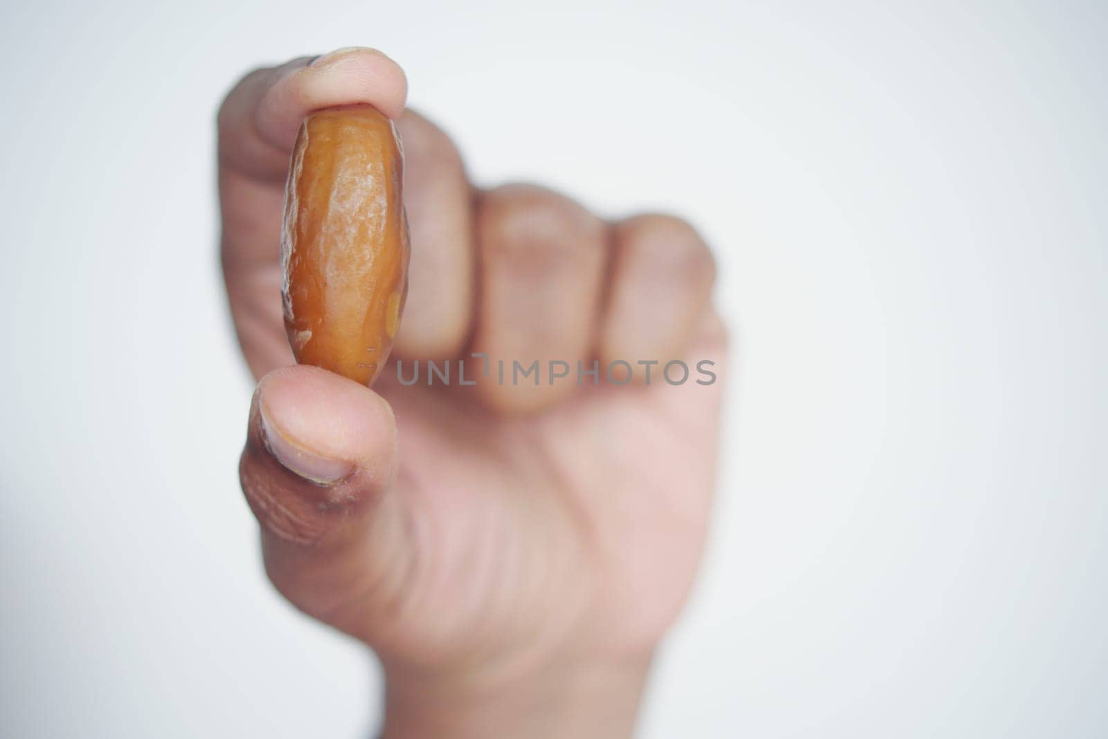 Close up of hand holding a date fruit .