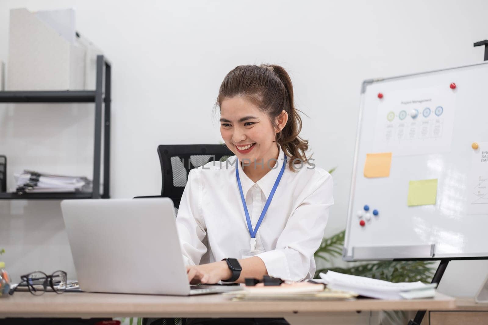 Beautiful determined business woman working using laptop recording data in modern office by wichayada