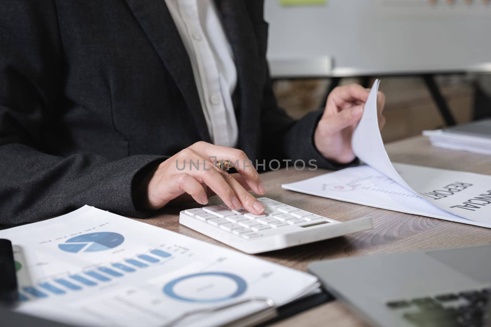 Asian female accountant working on calculations on table in office.