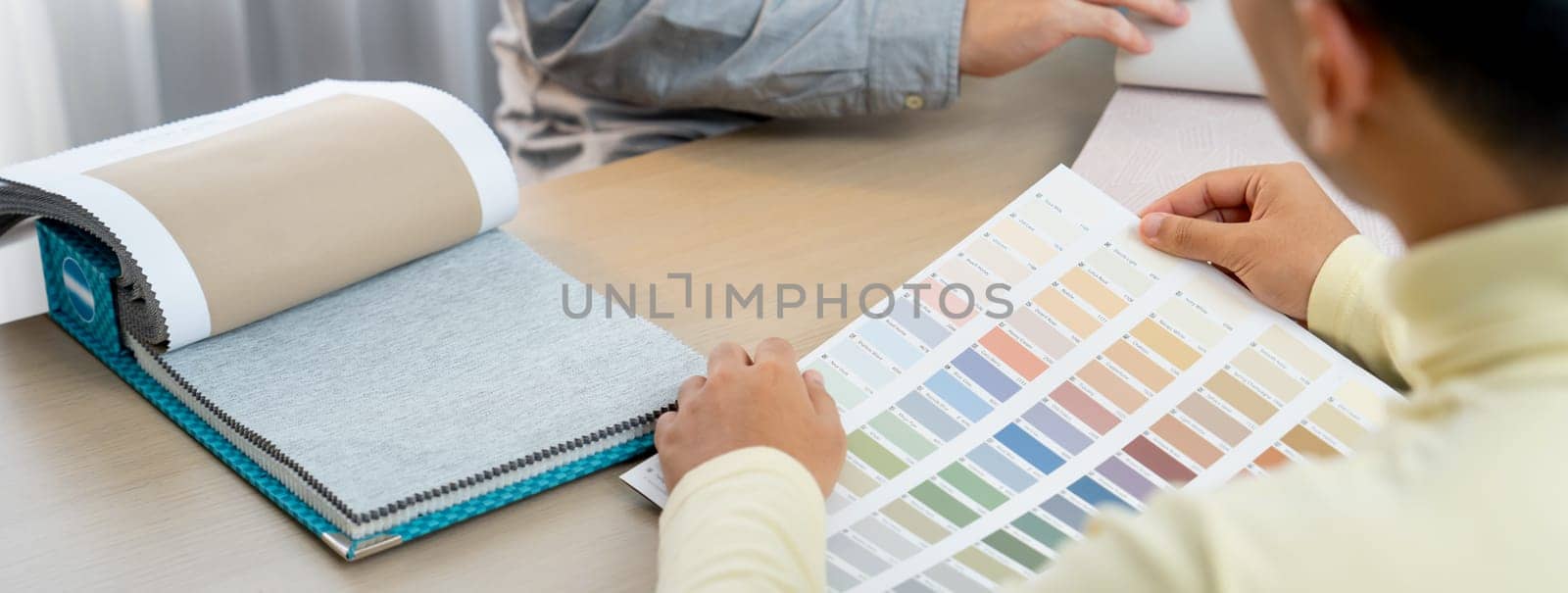 Professional architect and interior designer discussing about curtain material and appropriate color from color palette. Skilled interior designer presents material to customer. Closeup. Variegated.