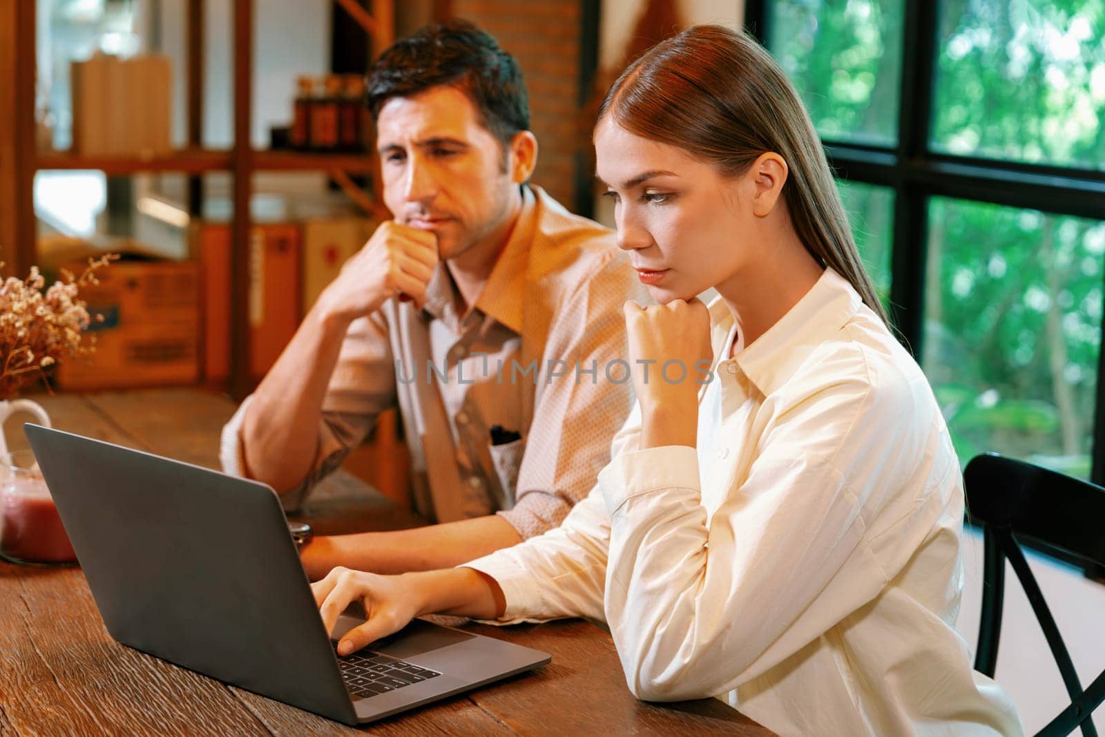 Young couple working remotely on laptop in cafe look tired and frustrated. Digital nomad freelancers or college students struggling to meet a deadline overwhelmed by workload. Expedient