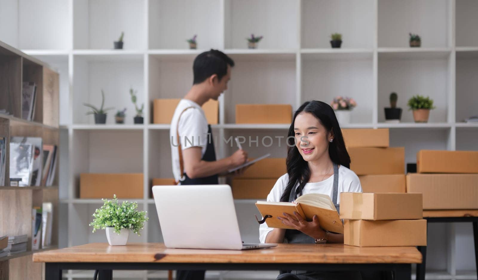 A couple of online sellers work together to take online orders and pack products for delivery to customers. by wichayada