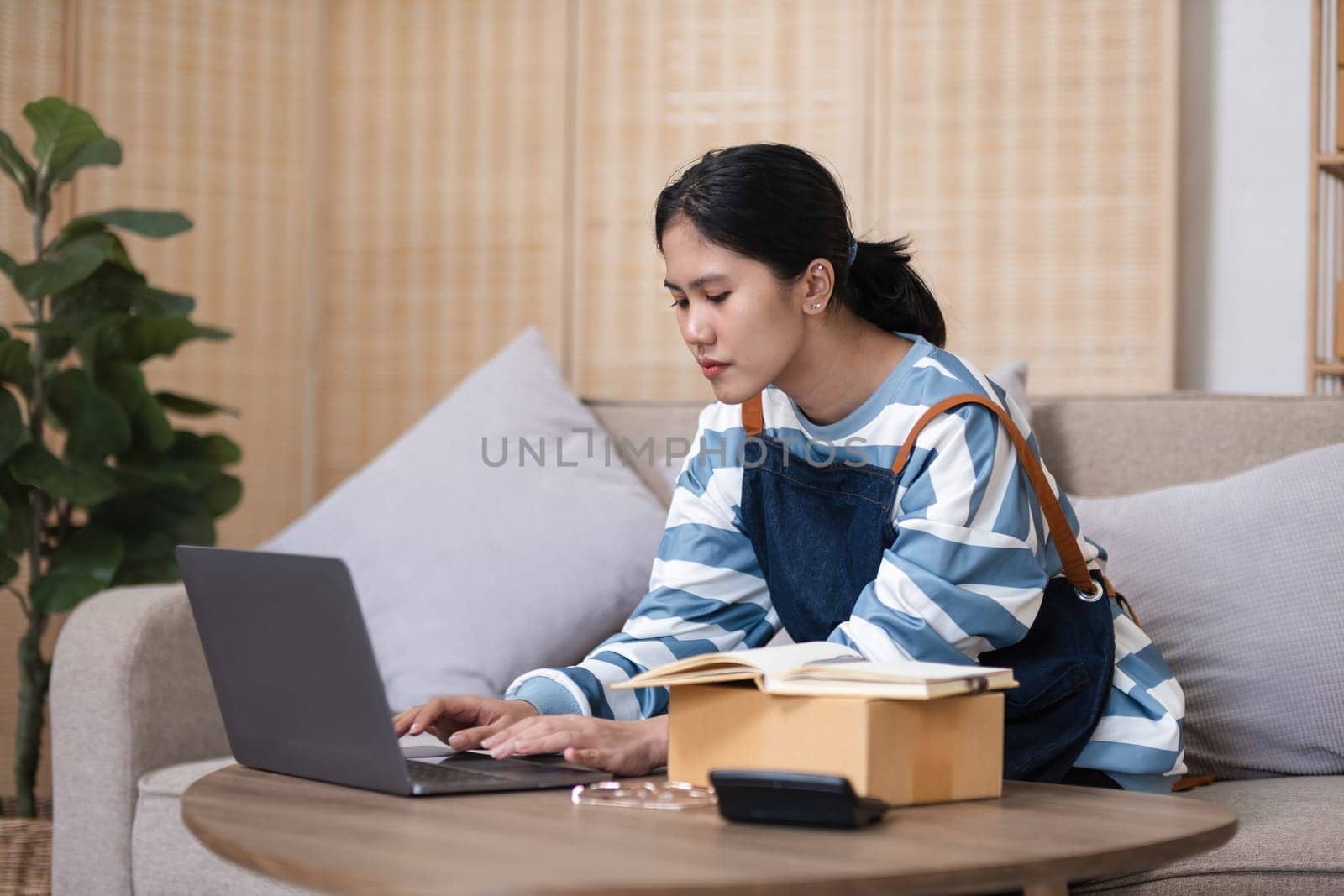 A small SME business owner feels tired while sitting on his home desk packing products into boxes. by wichayada