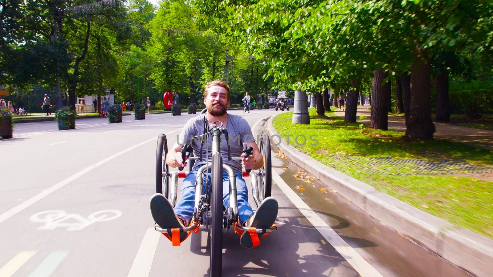 Face view of happy young disable man riding hand bike in the park. He smiling.