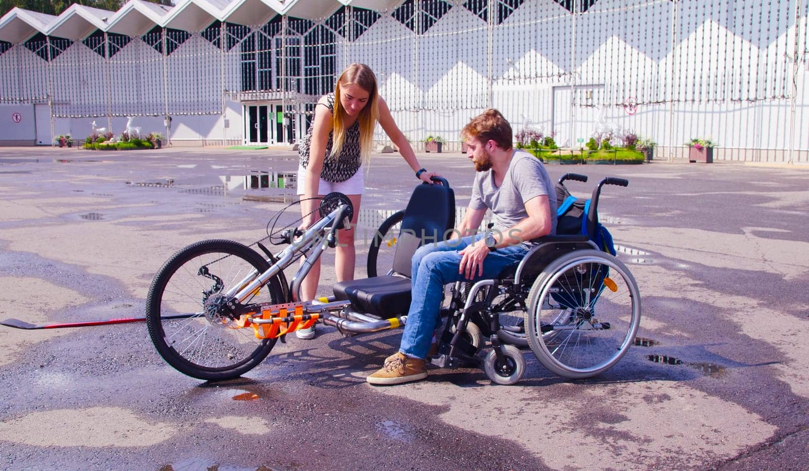 Young disable man in wheelchair near hand bike by Chudakov