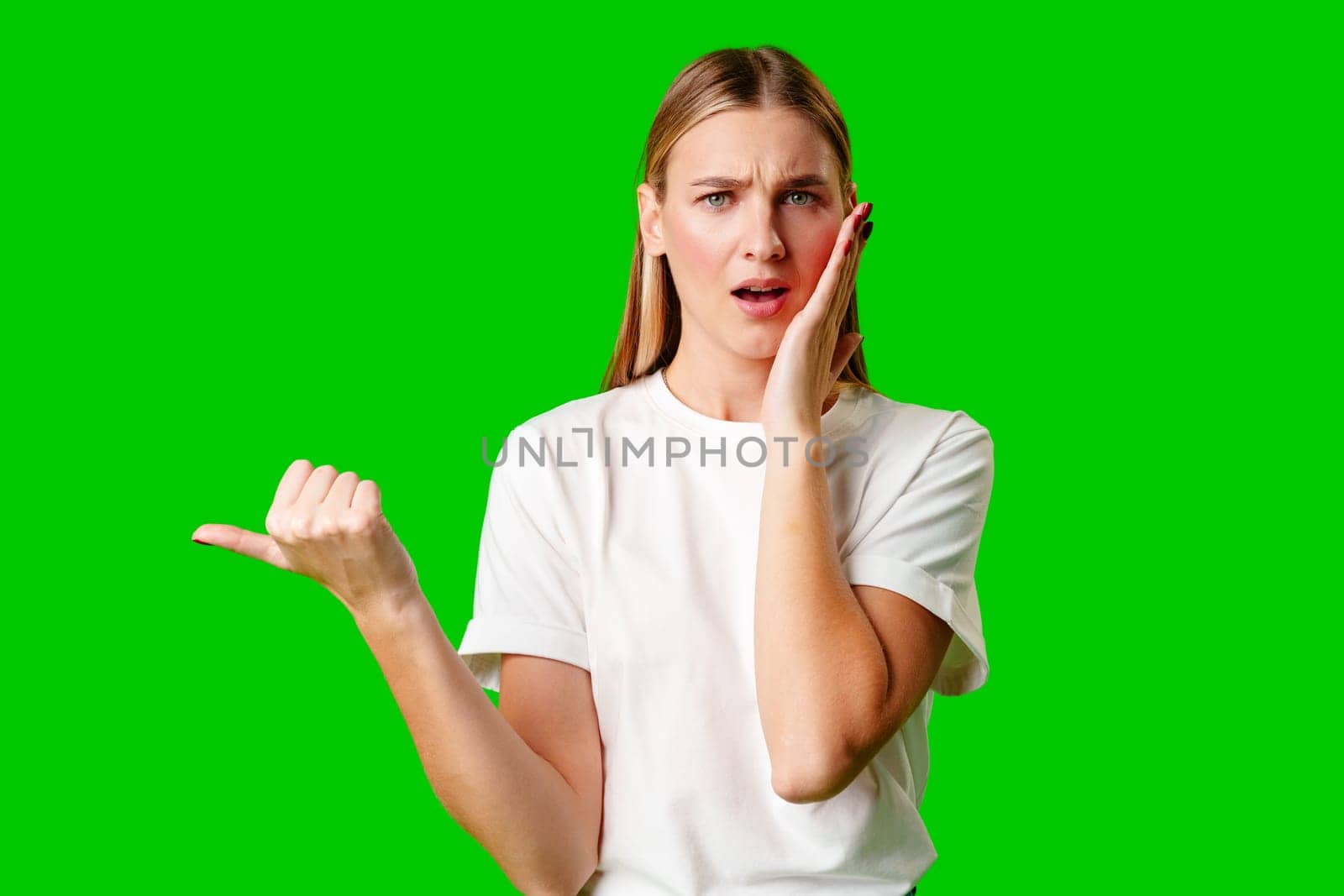 Young Woman Pointing at Something against green background by Fabrikasimf