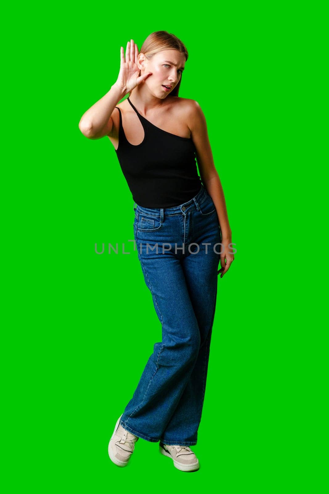 Young Woman in Black Top Holding Hand to Ear against green background