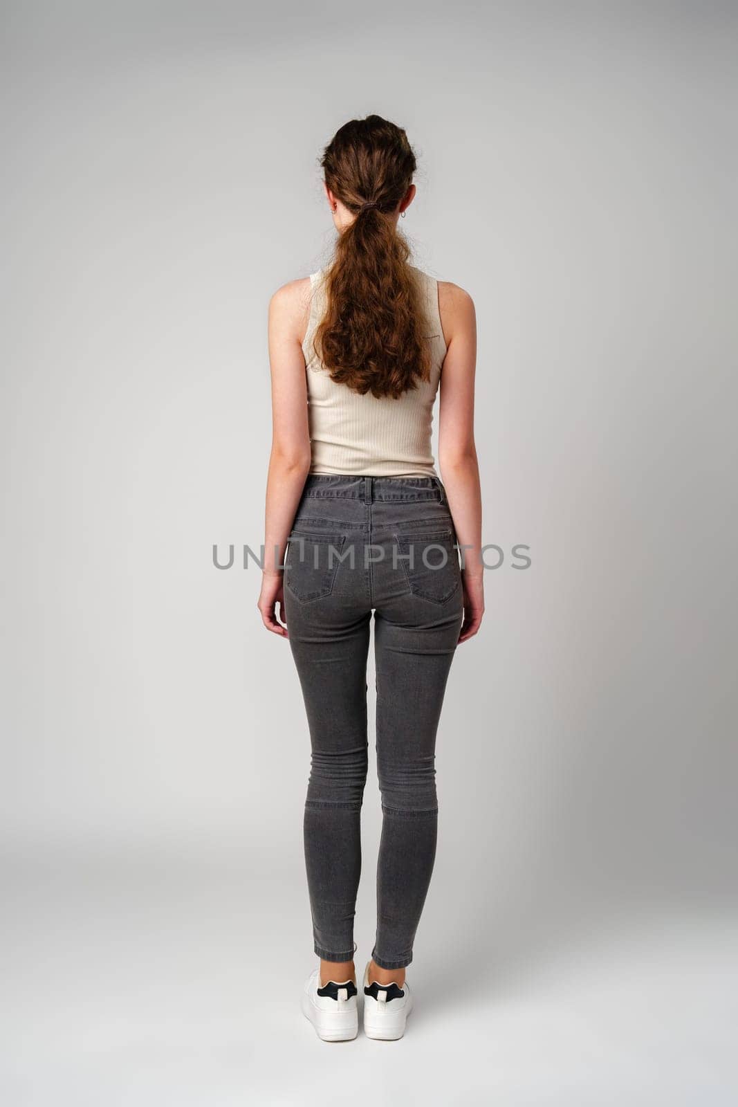 Young Woman Standing in Front of Gray Background Back view by Fabrikasimf