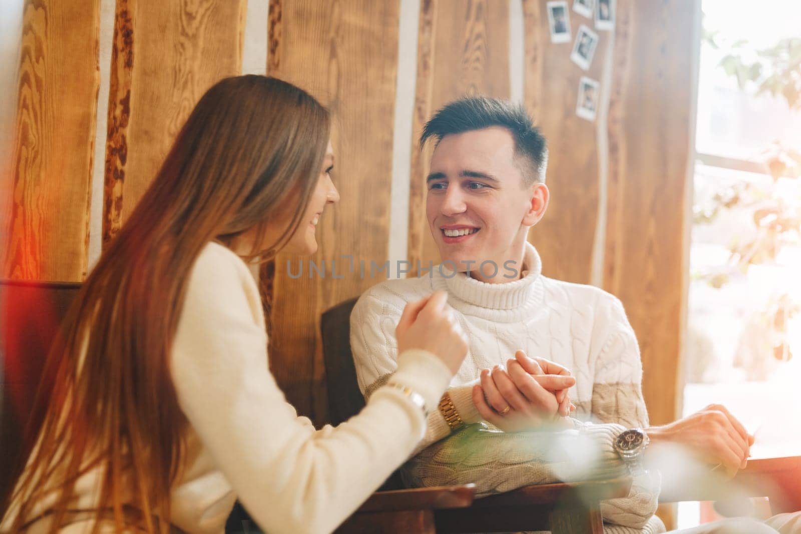 Young Couple Enjoying A Lighthearted Conversation At A Cozy Cafe During The Day by Fabrikasimf