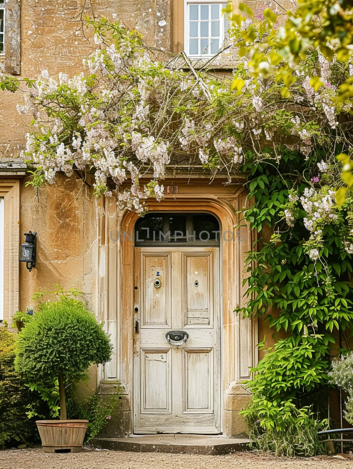 Entrance to a historic manor, framed by antique architectural elements and flanked by potted topiaries, features an aged door by Anneleven