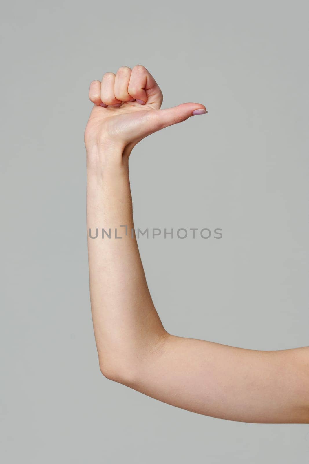 Female hand gesturing thumb up sign on gray background by Fabrikasimf