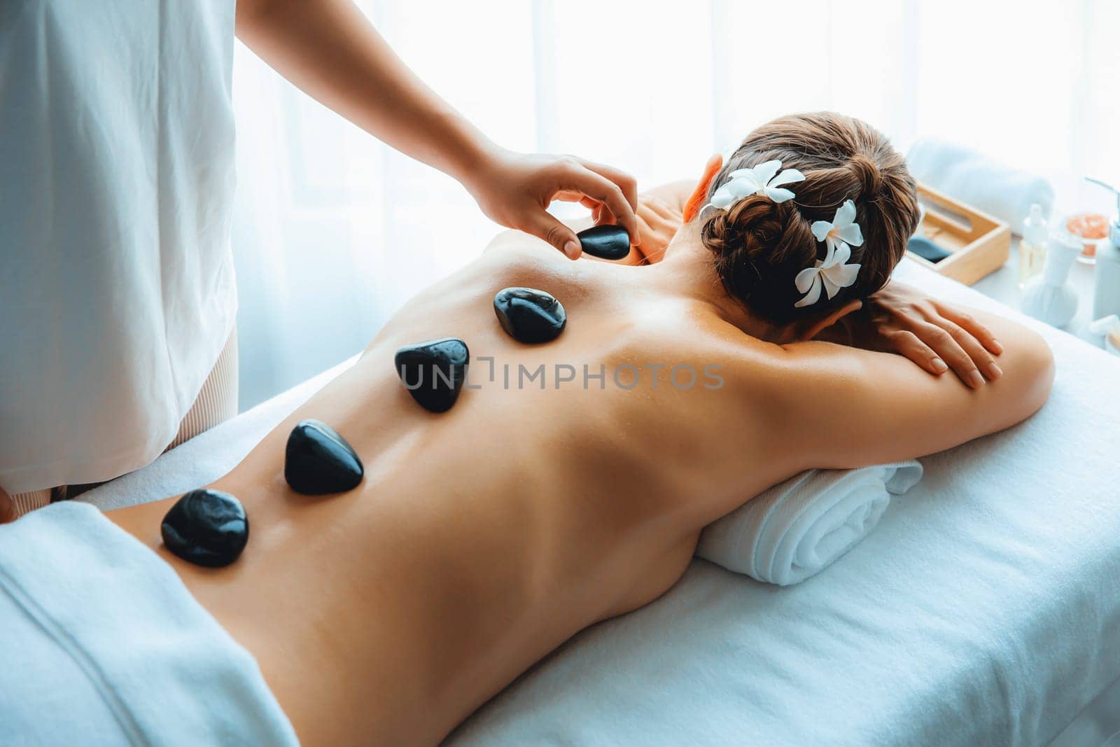 Hot stone massage at spa salon in luxury resort. Quiescent by biancoblue