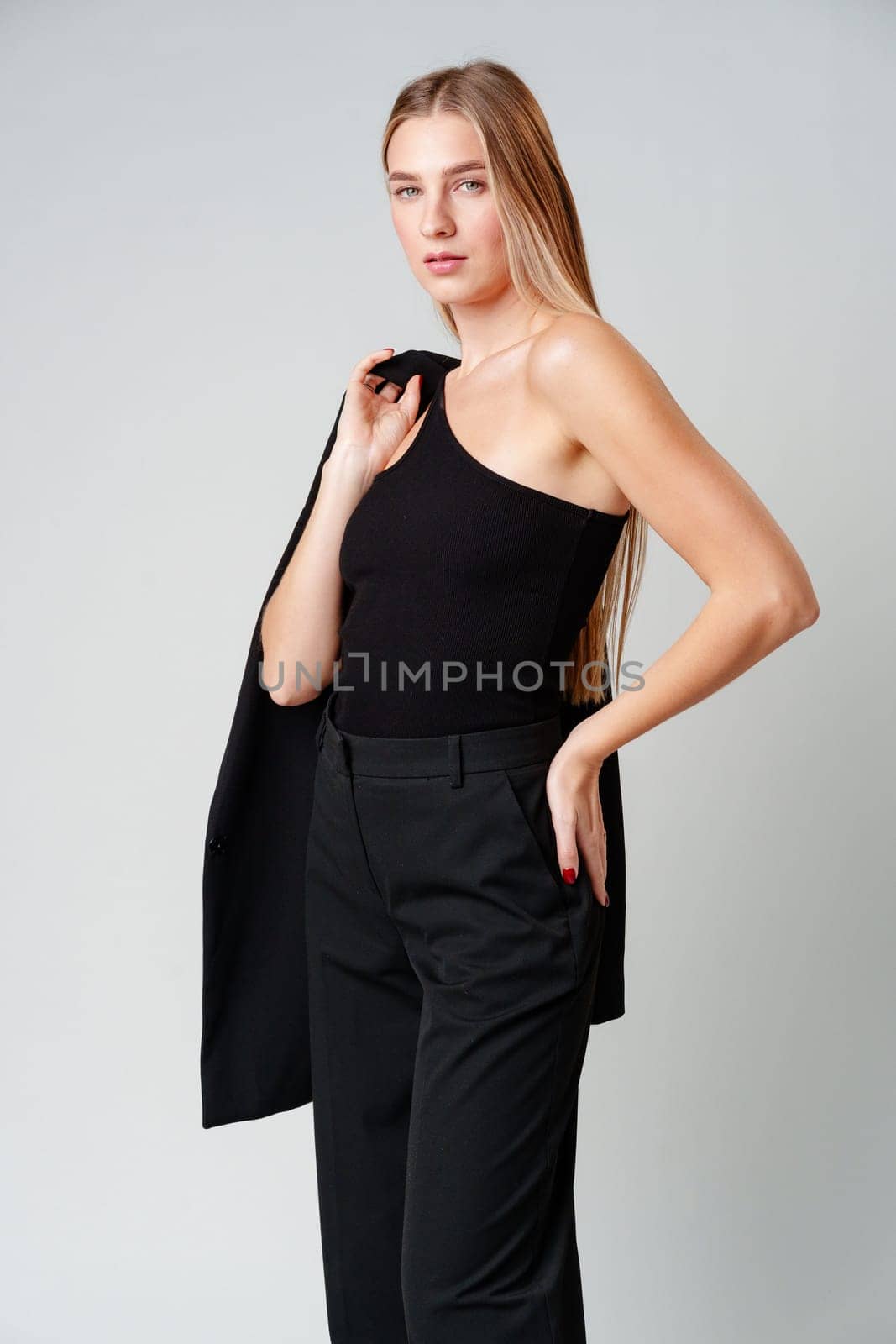 Young Woman Model in Black Top and Pants Posing on gray background by Fabrikasimf