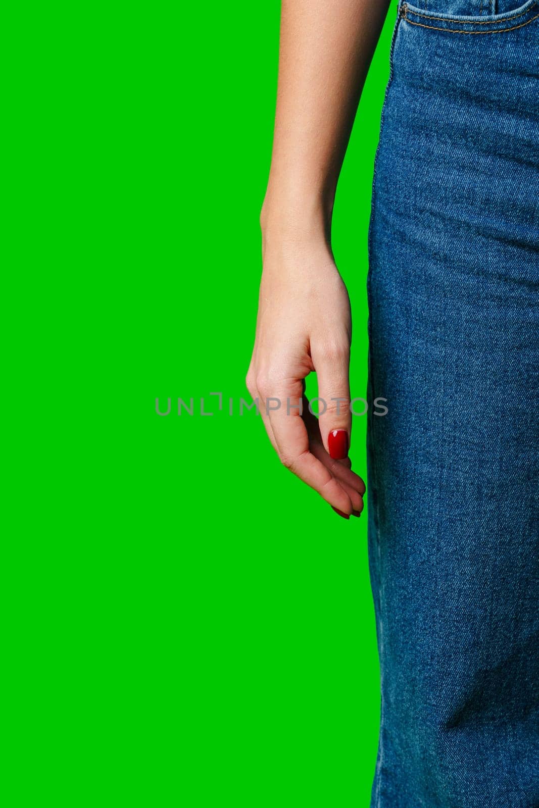 Woman Standing Sideways Wearing Denim Jeans Against a Green Background close up